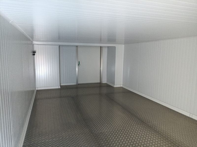 Interior de cámara frigorífica montada, con acceso abatible y suelo de aluminio antideslizante.